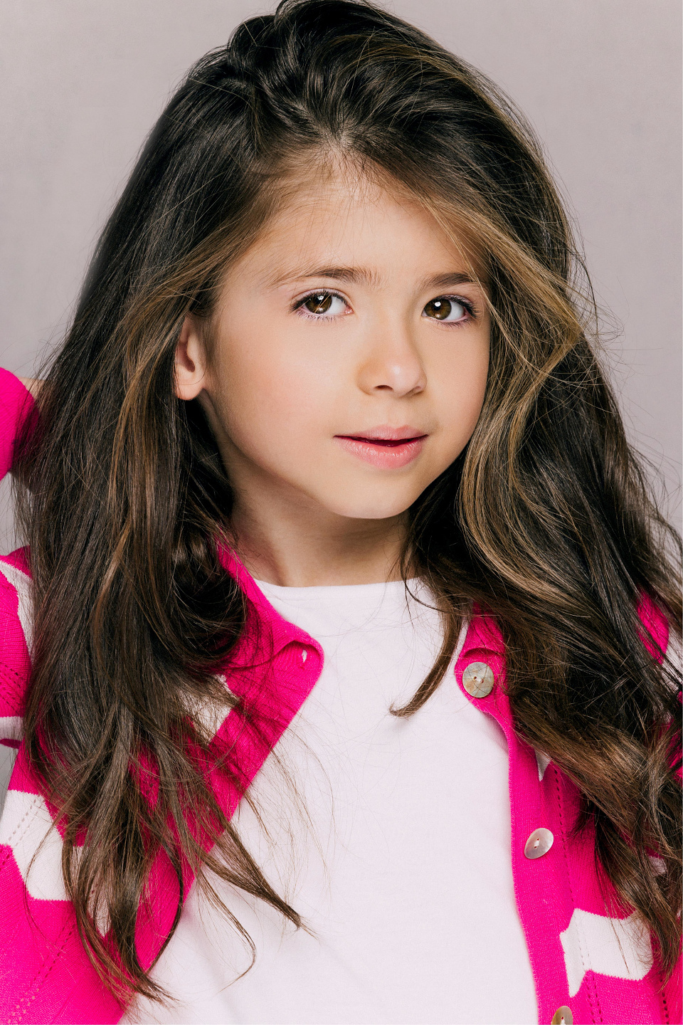 Young girl model with long wavy hair in a pink cardigan